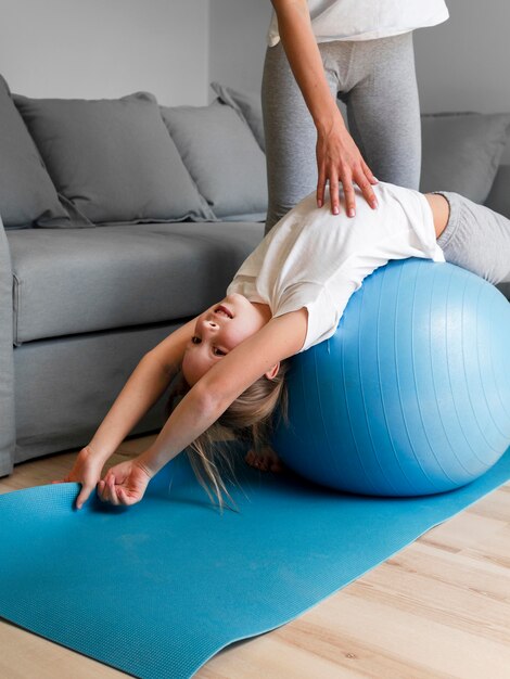 Mom helping girl to workout with ball