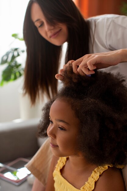 Мама помогает своему ребенку укладывать волосы в стиле афро