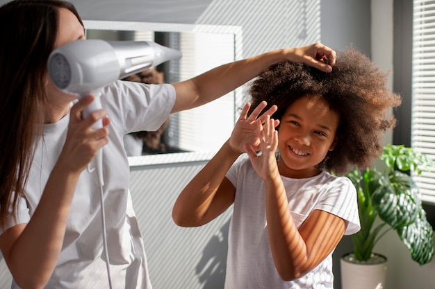 無料写真 子供がアフロヘアをスタイリングするのを手伝うママ