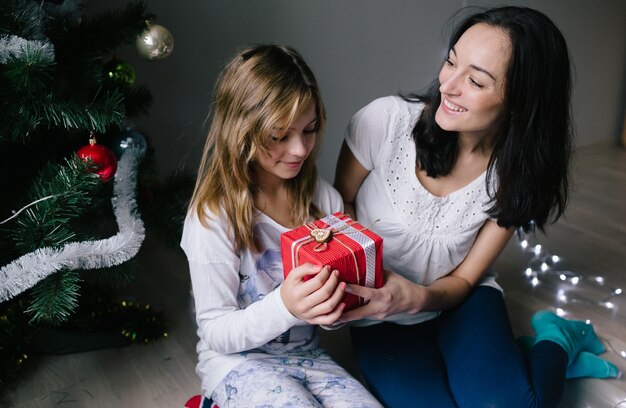 Mom and her cute daughter girl exchanging gifts.