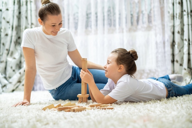 ママと娘は家の床で一緒に遊んでいます。幸せで笑顔