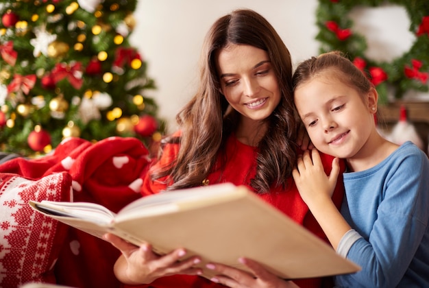 Mom and her daughter reading a book at Christmas