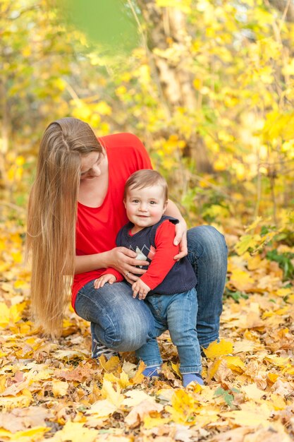 Mom holding little son surrounded by leaves