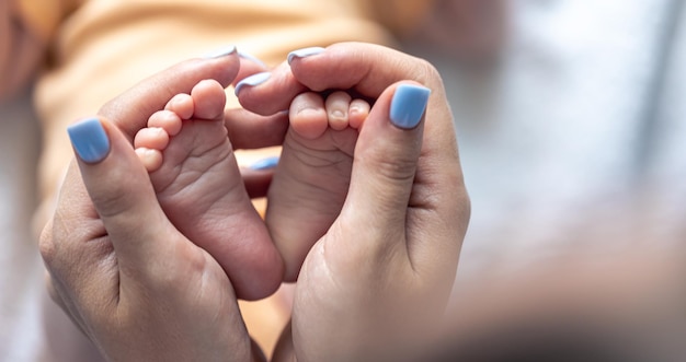 Mom holds the legs of a newborn baby in her hands