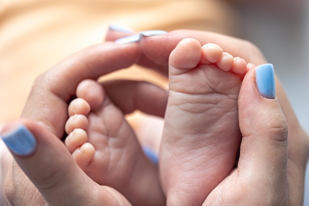 Foto gratuita la mamma tiene in mano le gambe di un neonato