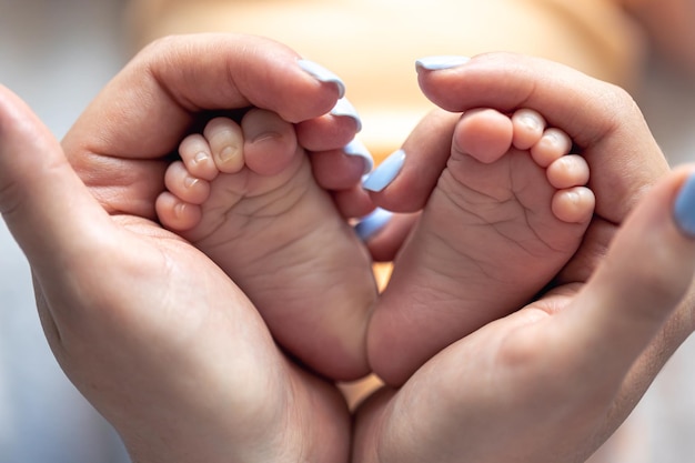 Free photo mom holds the legs of a newborn baby in her hands