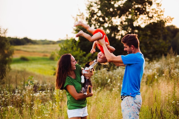 Mom holds little poppy while dad stands with son turned upside down 
