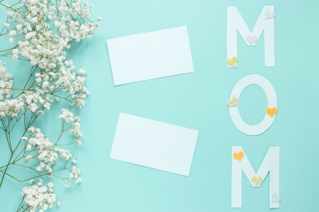 Mom inscription with flower branches and papers on table