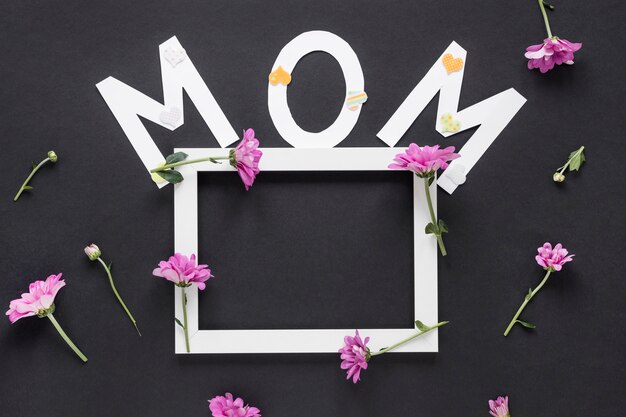 Mom inscription with frame and flowers on table
