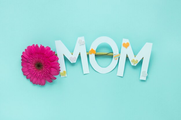 Mom inscription with gerbera flower on table