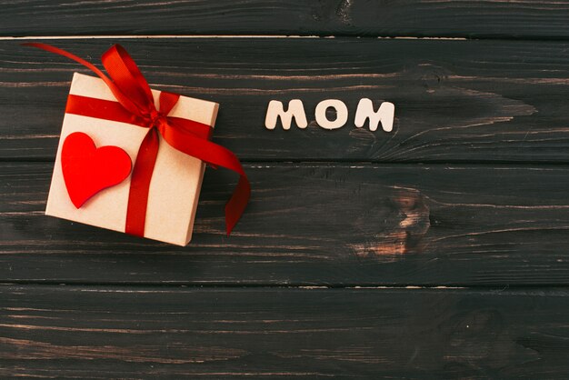 Mom inscription with gift box on table