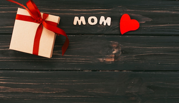 Mom inscription with gift box on wooden table