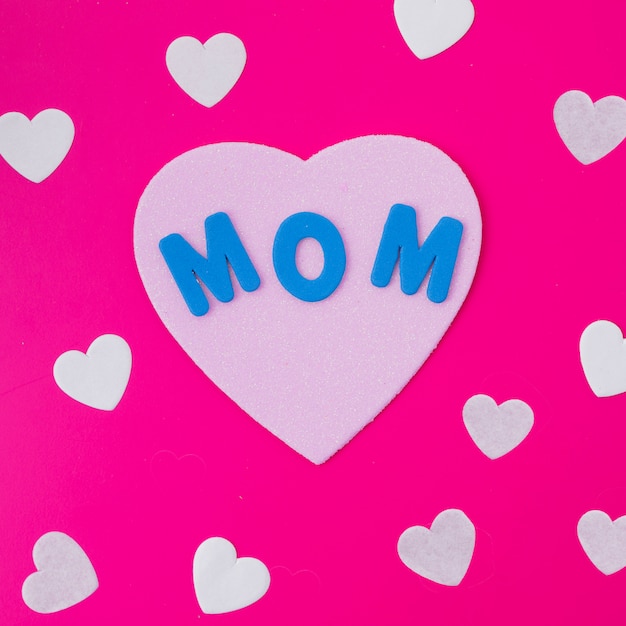 Mom inscription with paper hearts on pink table