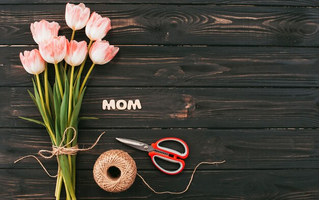 Mom inscription with tulips bouquet on dark table