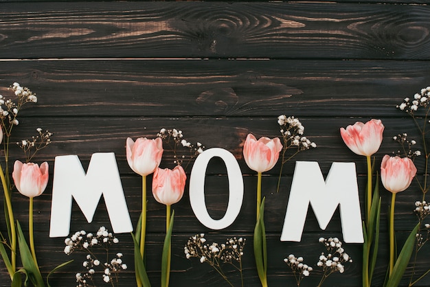 Mom inscription with tulips on dark wooden table