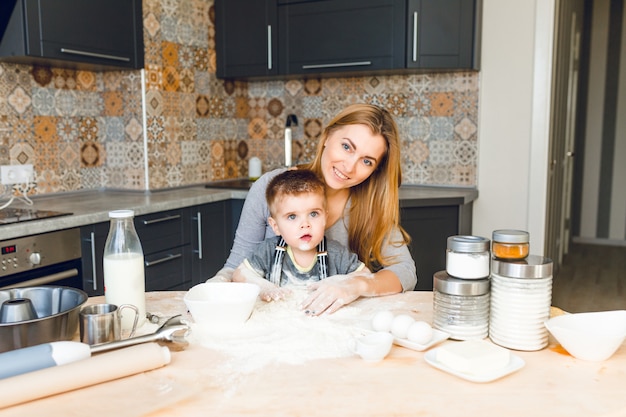 Foto gratuita mamma che gioca con il bambino in cucina. la cucina è fatta con colori scuri e stile rustico.