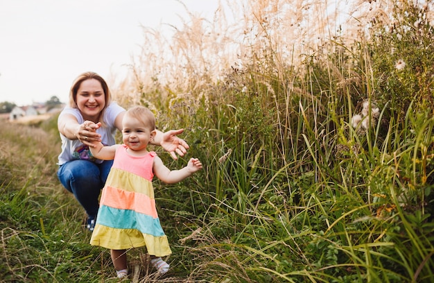 Foto gratuita la mamma gioca con la bambina nell'erba alta