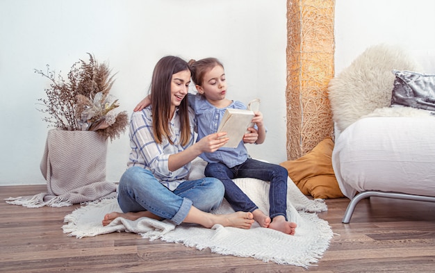 Mom reads a book with her daughters at home.