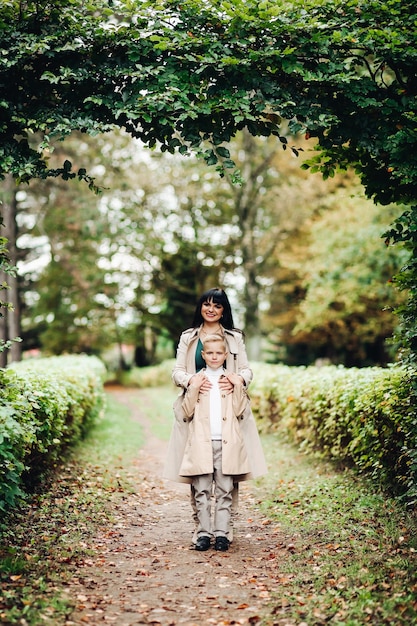 Mamma e figlio sono in buoni rapporti passeggiando nel parco chiacchierando con un look da famiglia alla moda