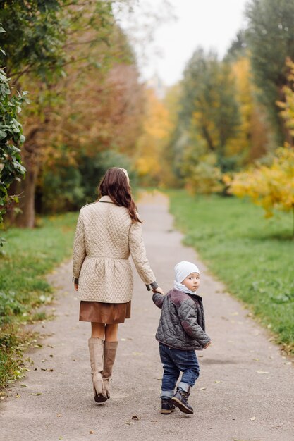 Mom and son walking and having fun together in the autumn park.