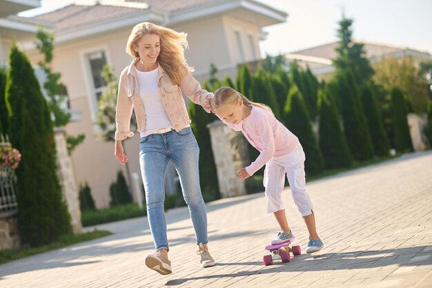 彼女がスケートボードをしている間、お母さんは女の子をサポートしています