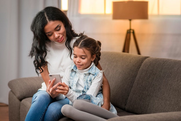 Free photo mom teaching daughter to use mobile