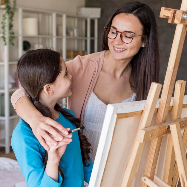 Mom teaching girl to paint at home