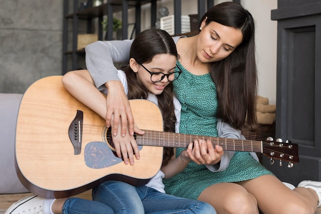 기타를 연주하는 소녀를 가르치는 엄마