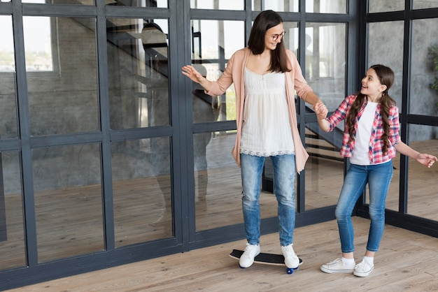 Free photo mom teaching girl to ride skateboard