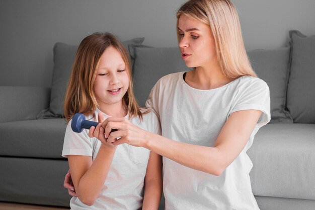 Mom teaching girl to train with weights