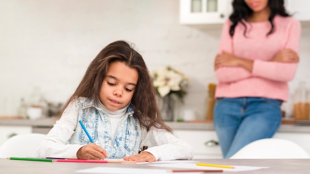 Mom watching little girl coloring