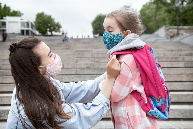 Mom with her little daughter, a schoolgirl, on the way to school. Coronavirus pandemic education