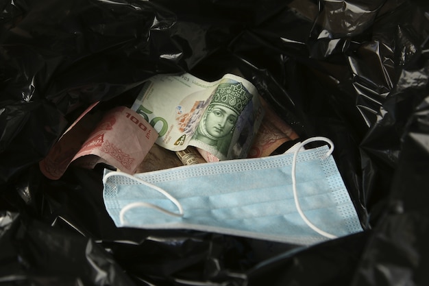 Money from around the world and a face mask inside a black plastic trash bag.