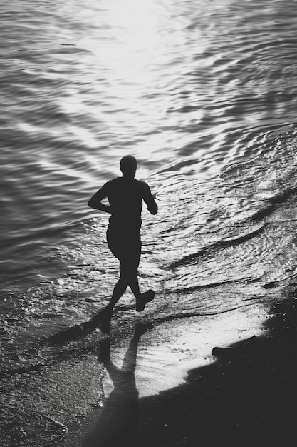 Foto gratuita ritratto monocromatico di un uomo che fa jogging sulla spiaggia