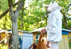 Foto gratuita ritratto monocromatico di un vestito d'apicoltura d'uso dell'uomo senior che posa alla sua arnia nel concetto di stile di vita di hobby di lavoro di agricoltore di occupazione di professione del copyspace del giardino.