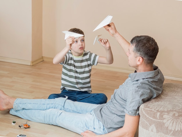 Foto gratuita padre monoparentale e figlio che giocano con gli aerei di carta