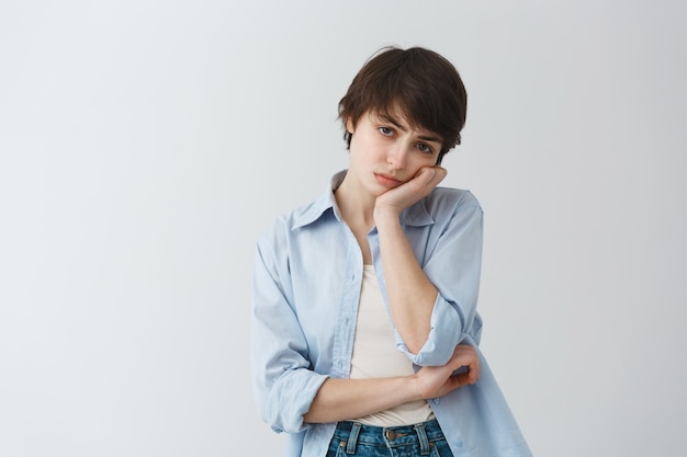 Free photo moody and reluctant cute girl tomboy looking unamused, leaning on palm and feeling bored