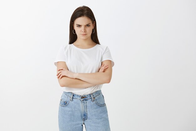 Moody young woman posing against white wall