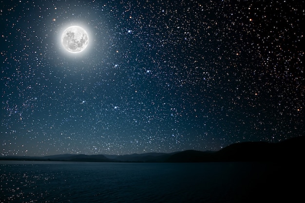明るい夜の星空を背景に月が海に反映されます。 | プレミアム写真
