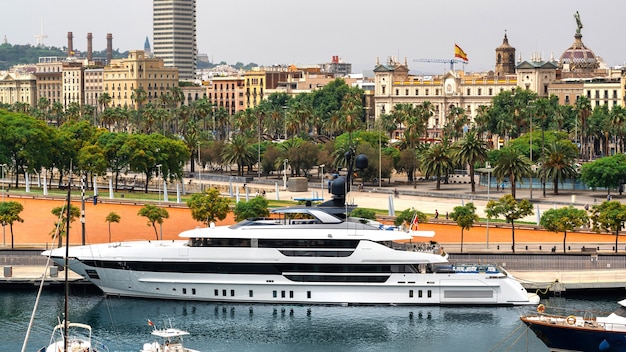 Moored yacht in the Mediterranean sea port, buildings, street, greenery in Barcelona, Spain