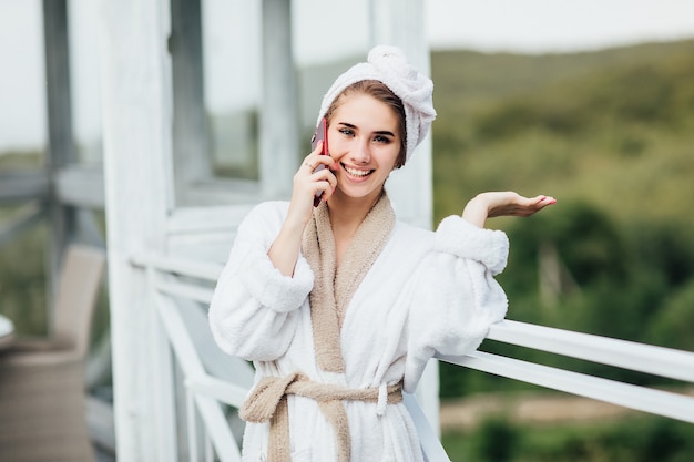 Утро на террасе отеля в горах. Женщина разговаривает по телефону и имеет красивое лицо.