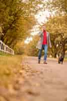 Foto gratuita mattinata al parco. uomo che fa una passeggiata mattutina con un cane e parla al telefono
