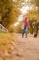 Free photo morning in the park. man having a morning walk with a dog and talking on the phone