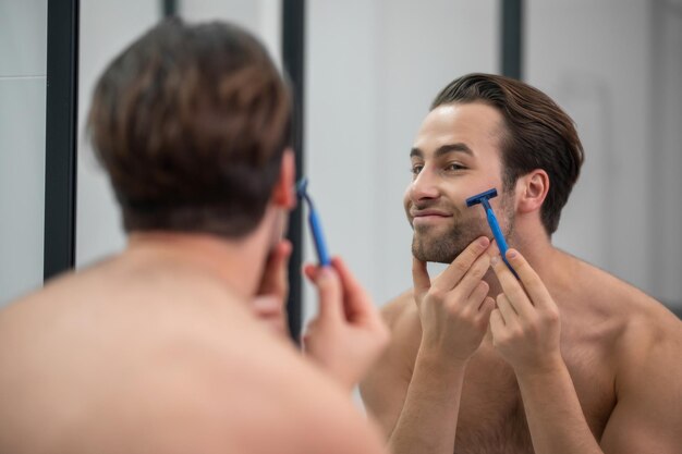 朝の手順。鏡で剃っている若い男