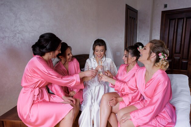 Morning tradition of bridesmaids and bride with champagne, silky nightwears, celebration