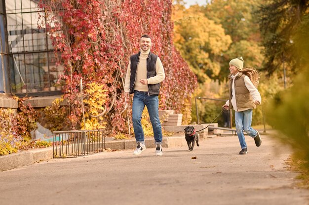 Morning walk. A man and a girl running with a dog