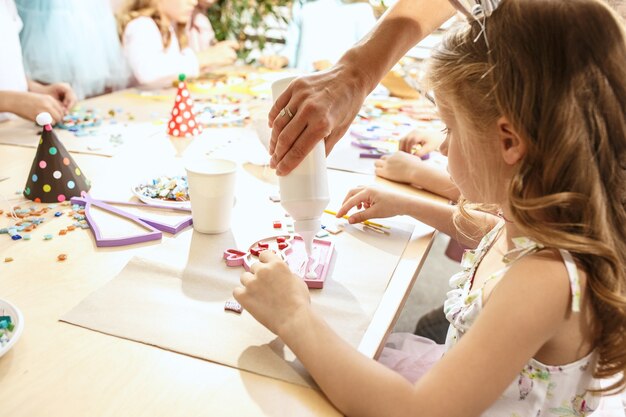 The mosaic puzzle art for kids, children's creative game. The hands are playing mosaic at table. Colorful multi-colored details close up. Creativity, children's development and learning concept