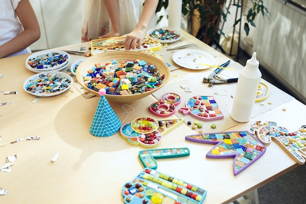 mosaic puzzle art for kids, children's creative game. hands are playing mosaic at table. Colorful multi-colored details close up.