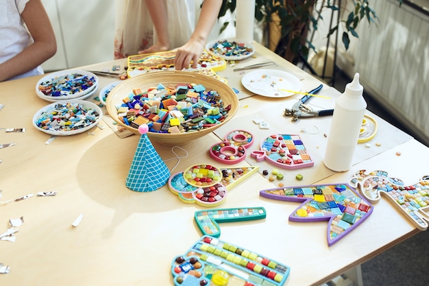 мозаика-пазл для детей, детская творческая игра. руки играют в мозаику за столом. Красочные разноцветные детали крупным планом.