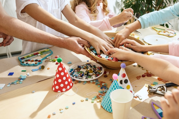 Free photo mosaic puzzle art for kids, children's creative game. hands are playing mosaic at table. colorful multi-colored details close up.